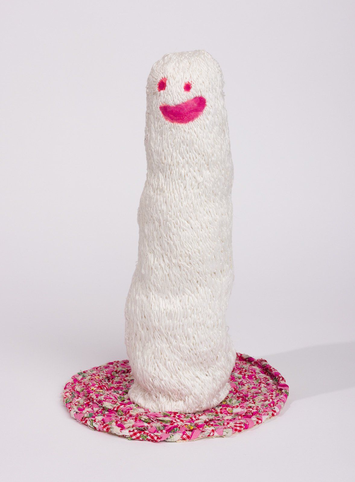 A white sculpture with a pink smiley face on it.