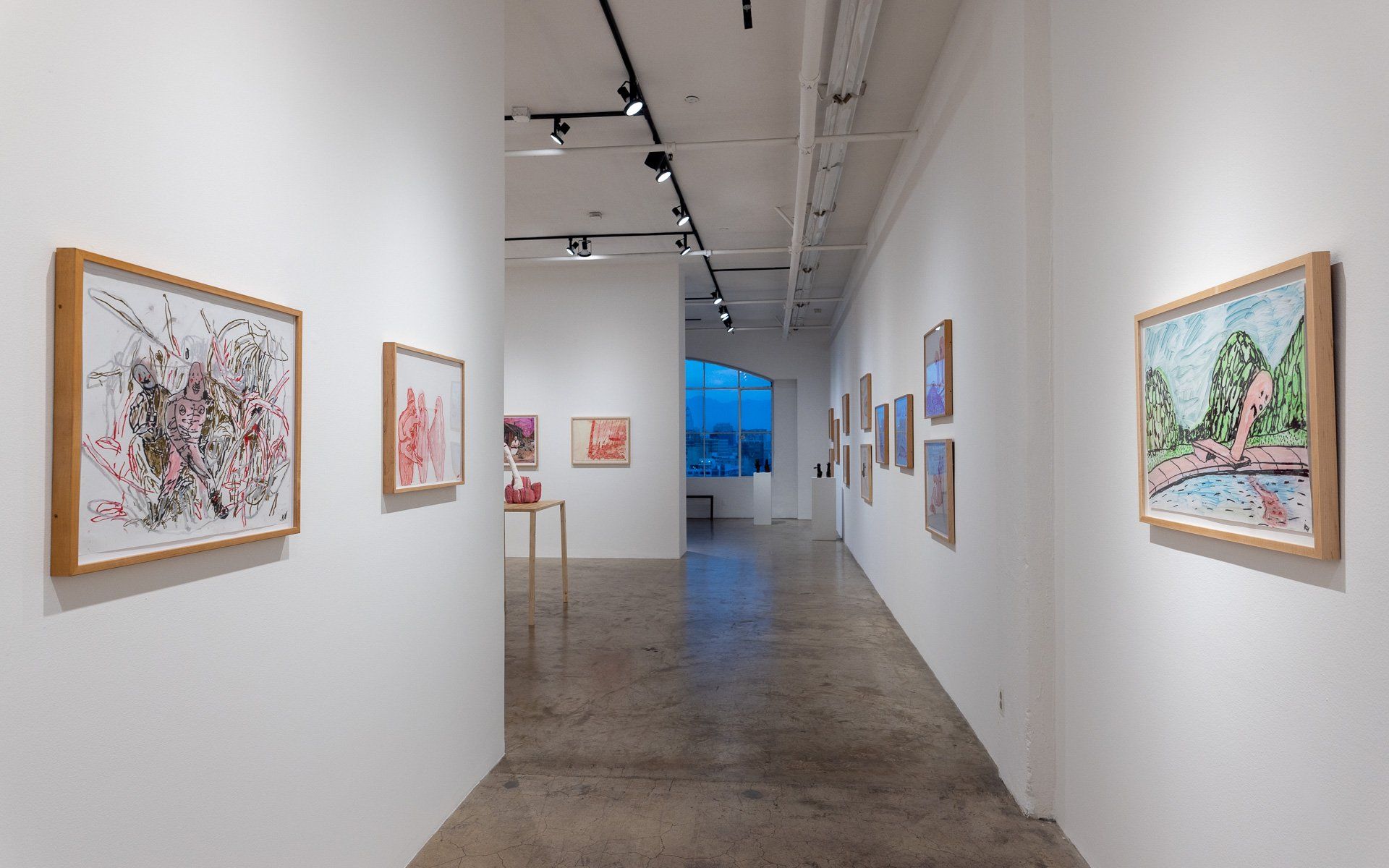 A long hallway with paintings on the wall in Track 16 Gallery.