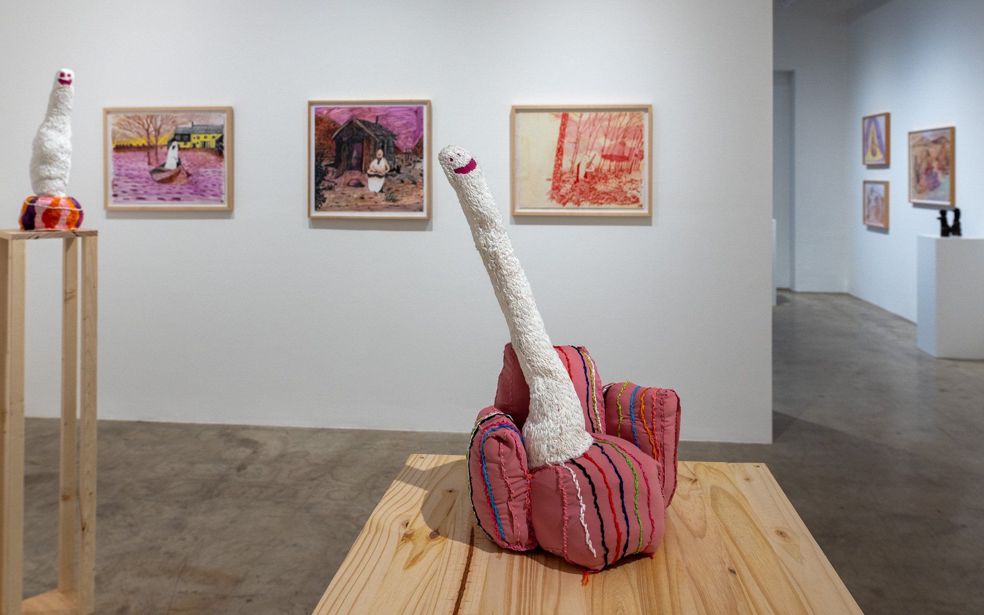 A sculpture of a chair is sitting on a wooden table in Track 16 Gallery.
