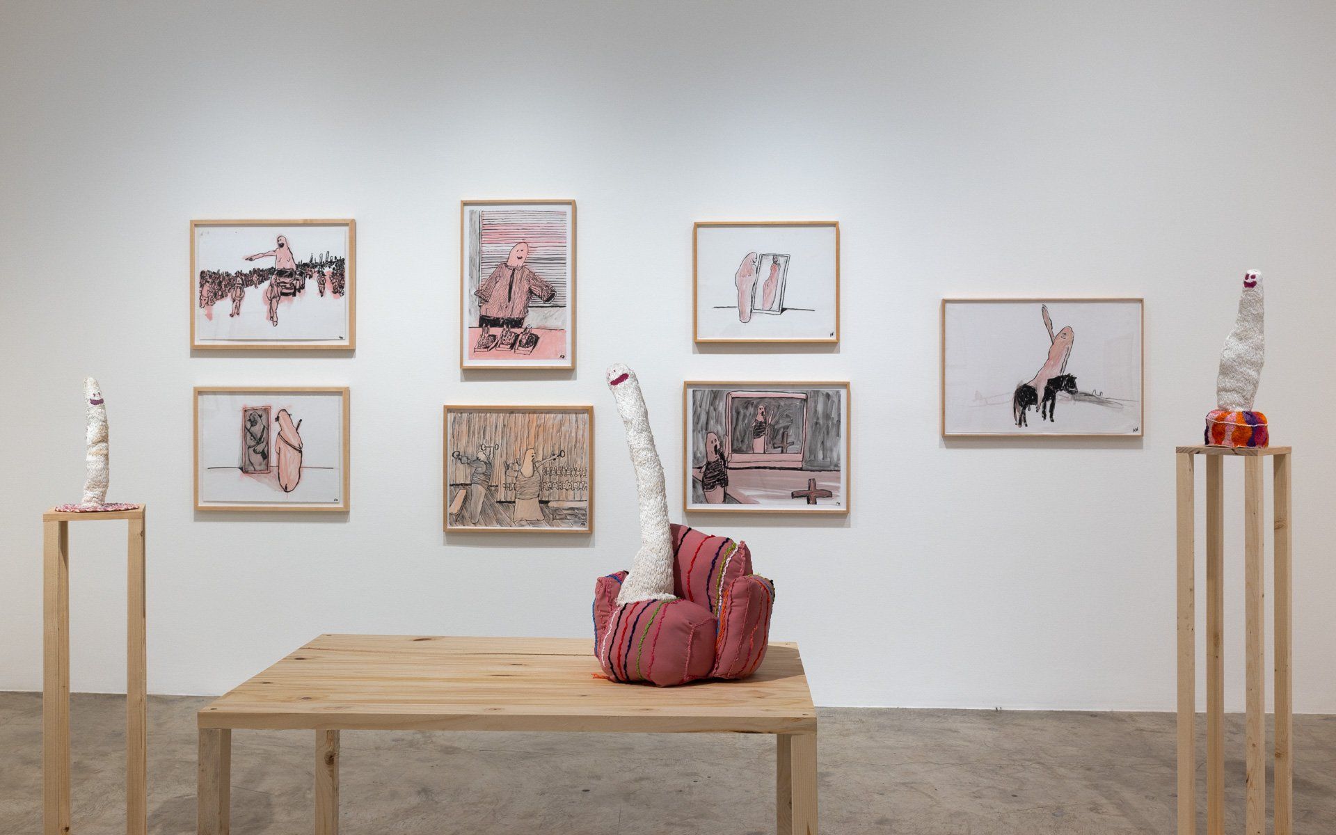 A wooden table is sitting in front of a wall with paintings on it.