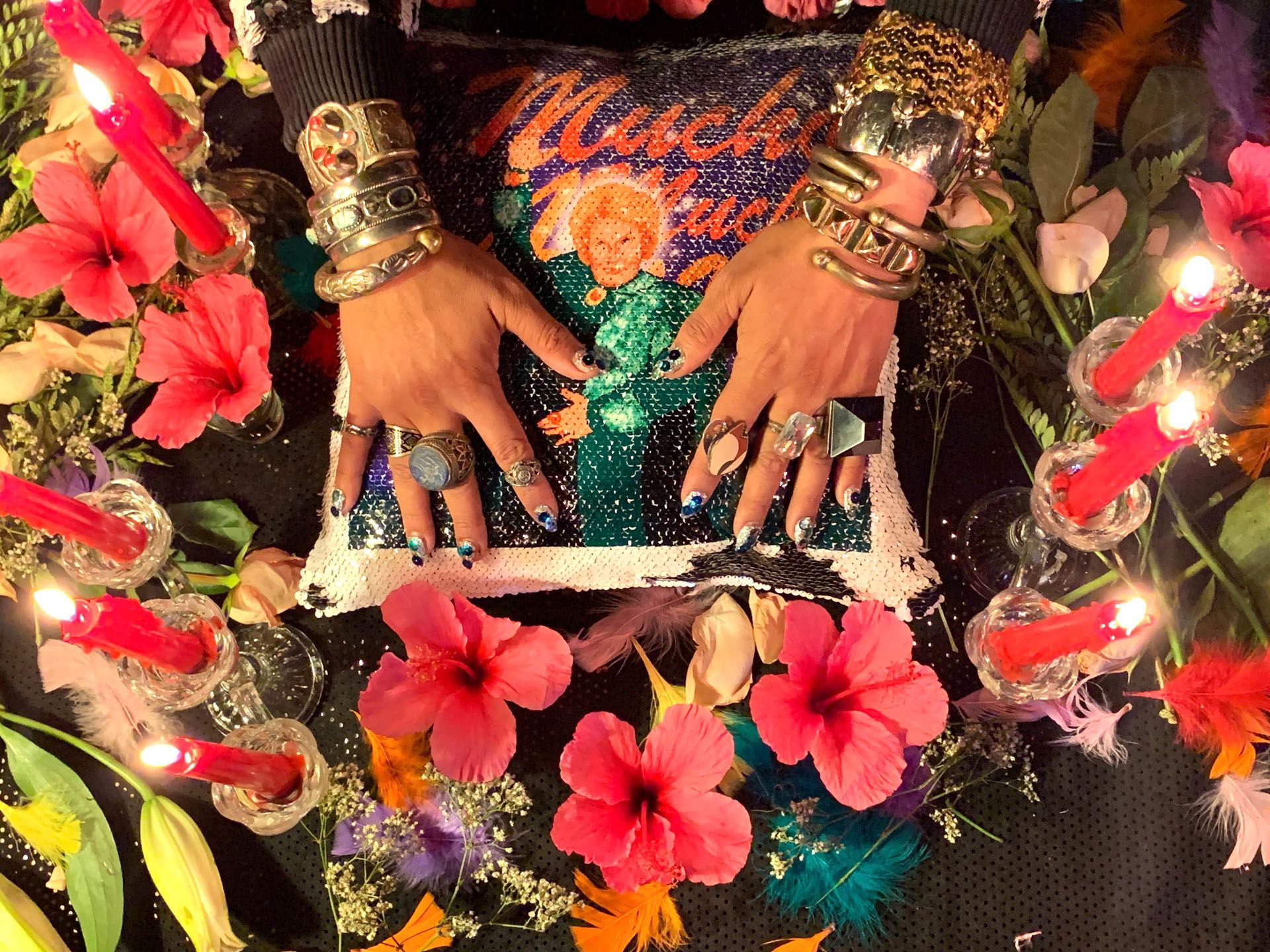 A woman 's hands are on a pillow surrounded by flowers and candles.
