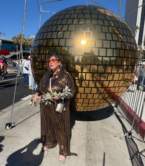 Nao Bustamante standing in front of an 8 foot disco ball.