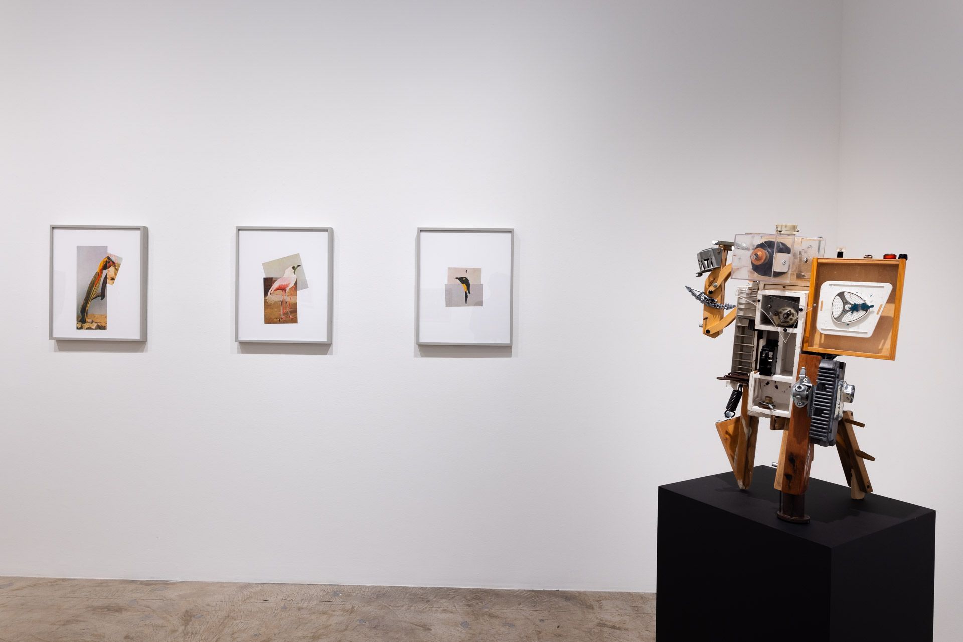 A room with three paintings on the wall and a sculpture on a pedestal.