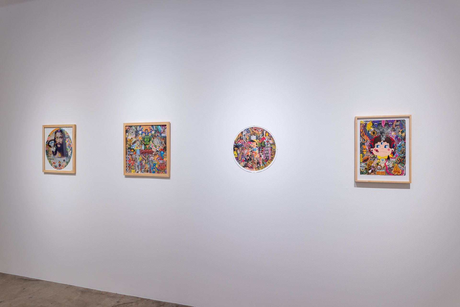 A row of paintings are hanging on a white wall in a museum.