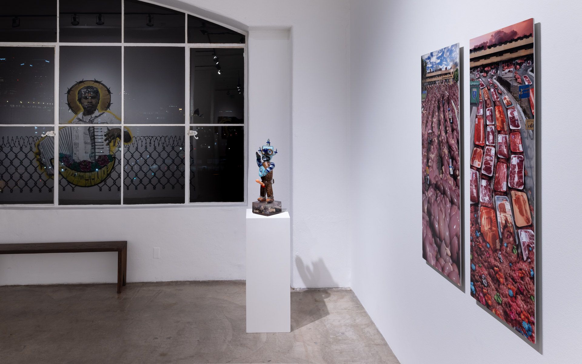 A room with a statue on a pedestal and two paintings on the wall.