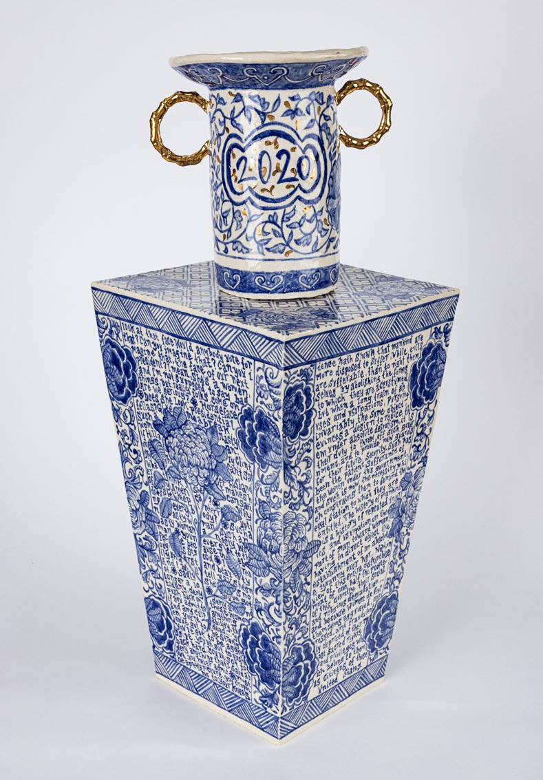 A blue and white vase is sitting on top of a square box.