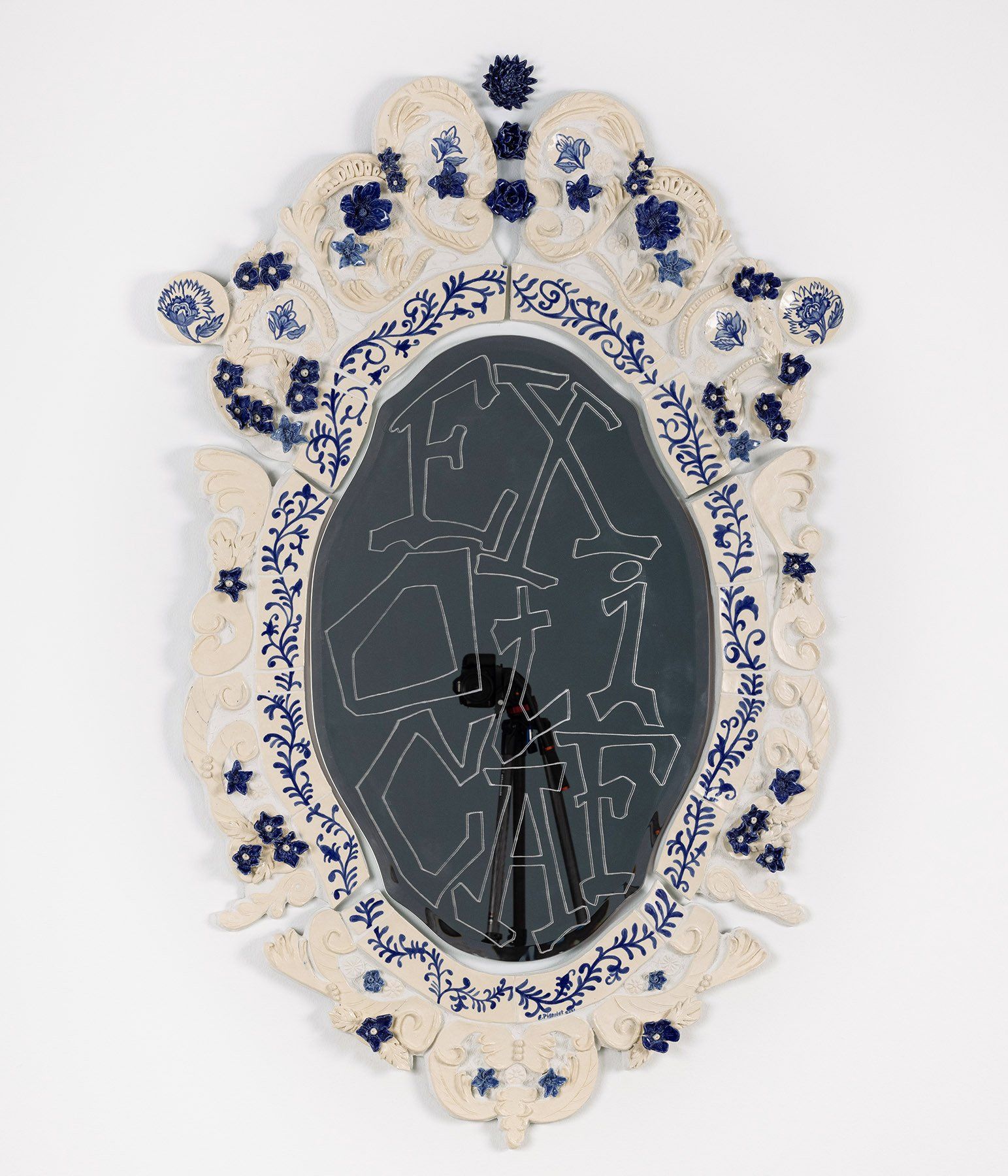 A mirror with a blue and white frame on a white wall