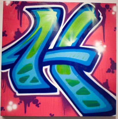 The letter k is painted in blue and green on a pink background