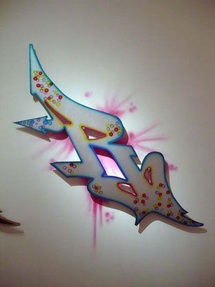 A colorful graffiti letter r is painted on a white wall