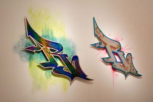 Two graffiti letters are painted on a white wall.