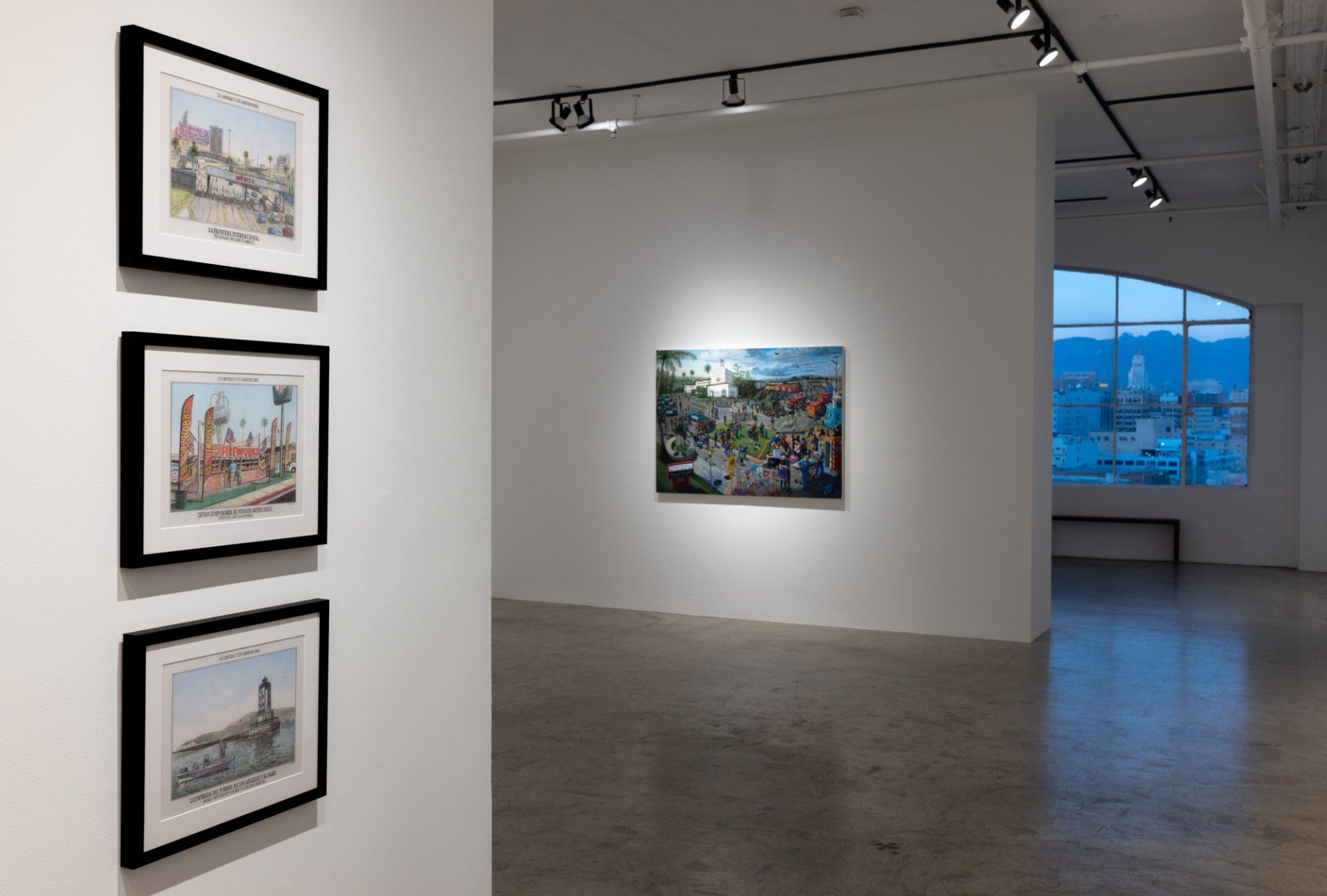 A room with three paintings on the wall and a window.