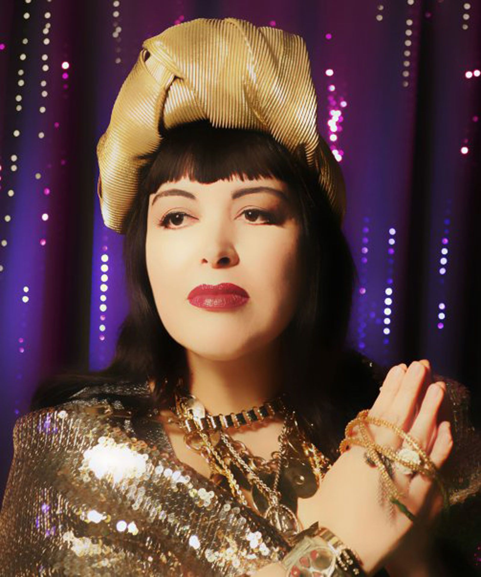 A woman wearing a gold top and a gold hat