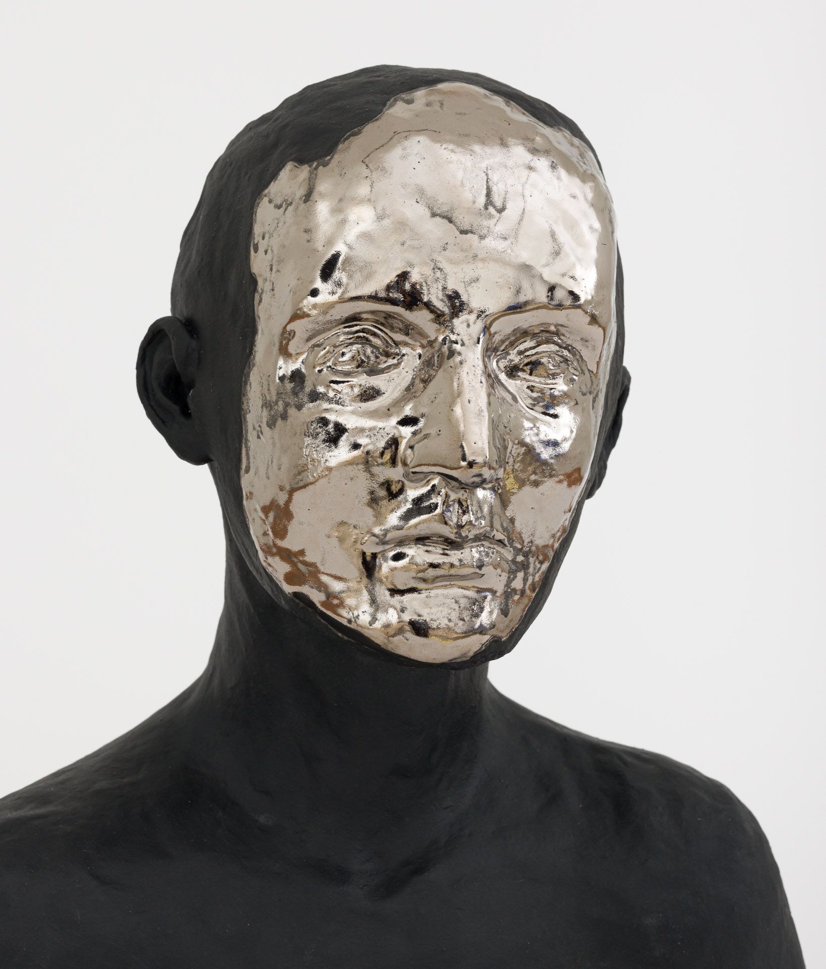 Black mannequin torso wearing a reflective silver face mask against a plain light background
