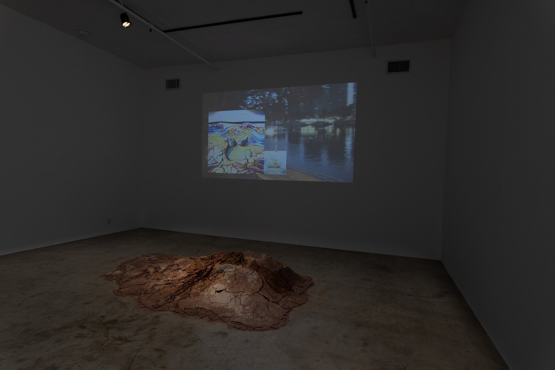 A room with a projector screen on the wall and a pile of dirt on the floor.