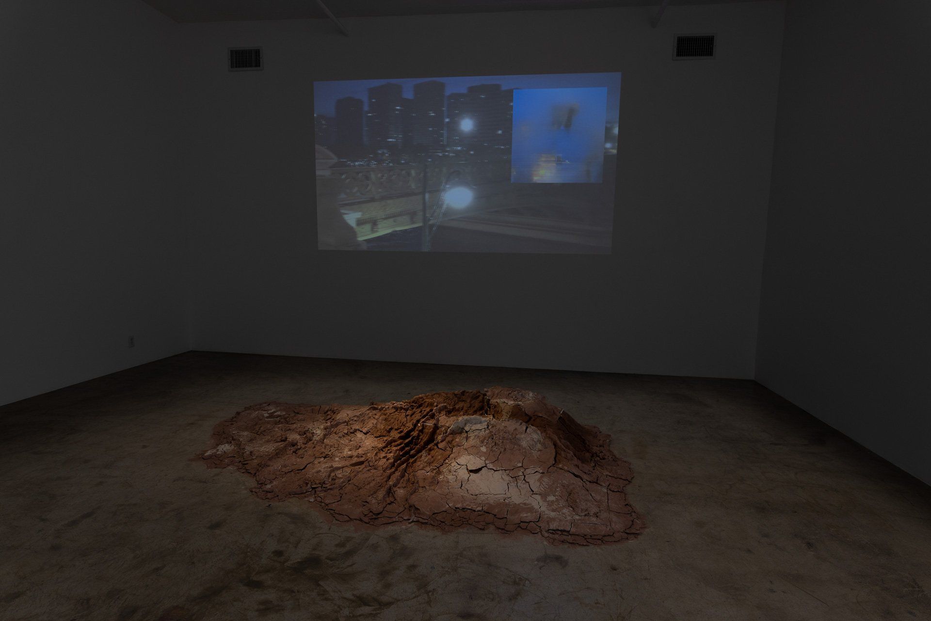 A room with a projector screen on the wall and a pile of dirt on the floor.