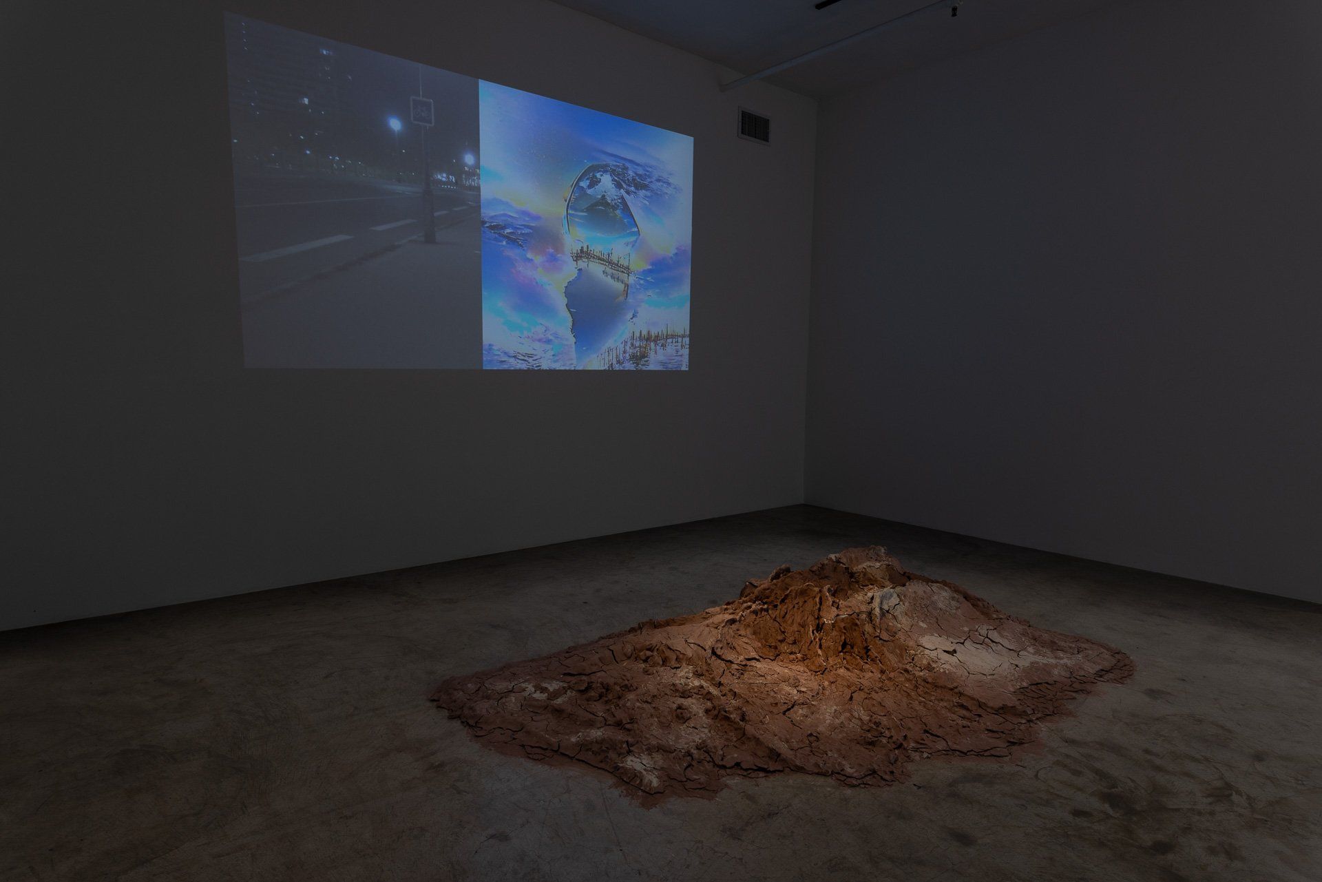 A room with a projector screen on the wall and a pile of dirt on the floor.