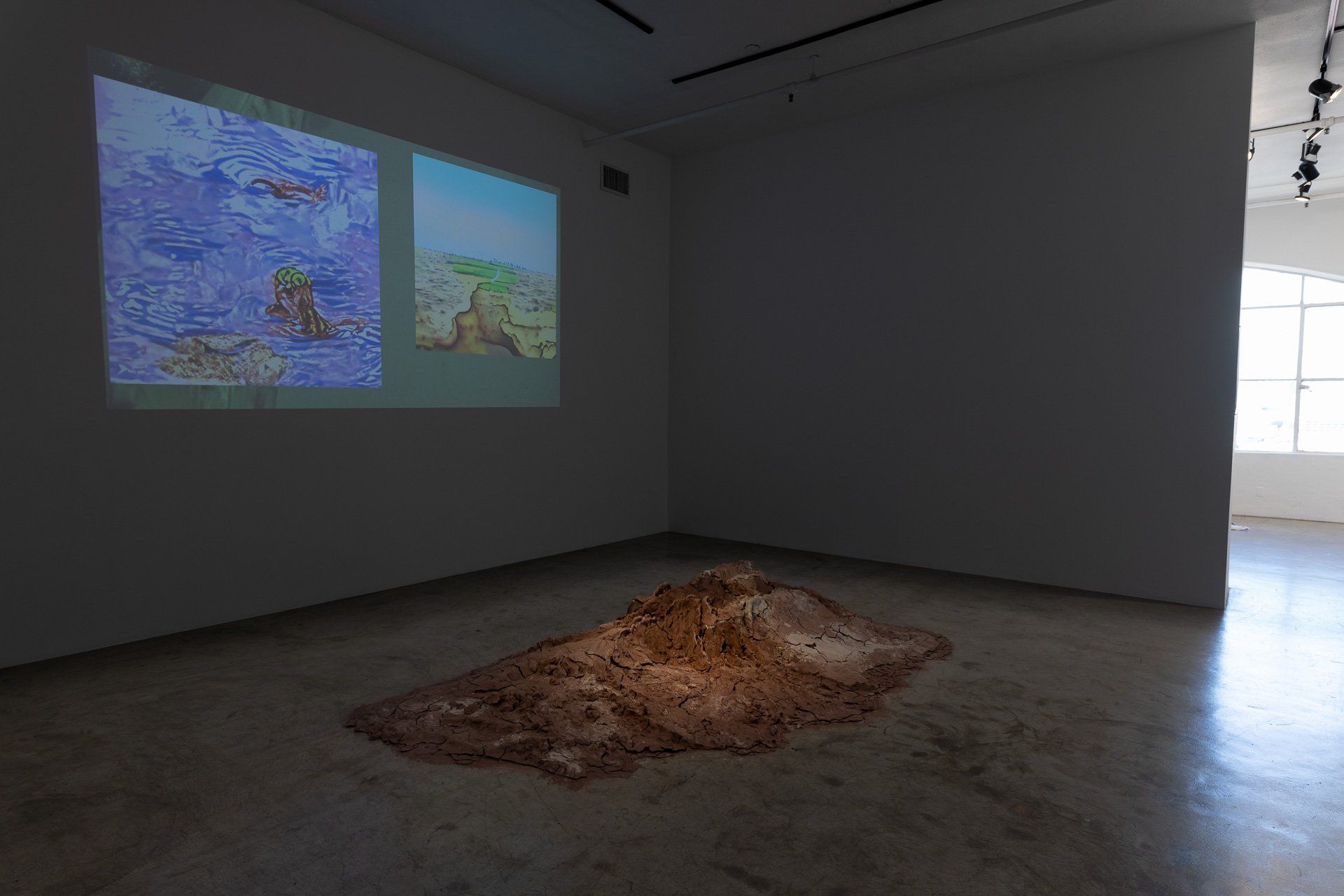 A room with a projector screen on the wall and a pile of dirt on the floor.