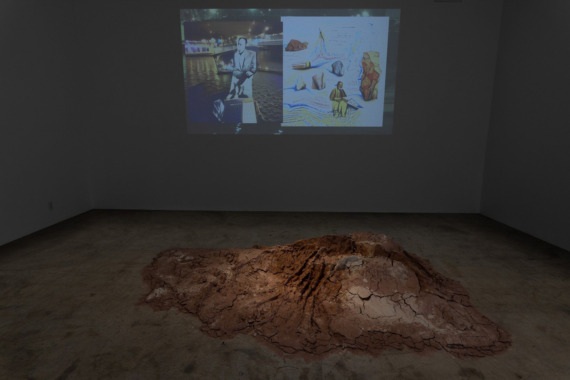 A room with a large pile of dirt on the floor and a projector screen on the wall.