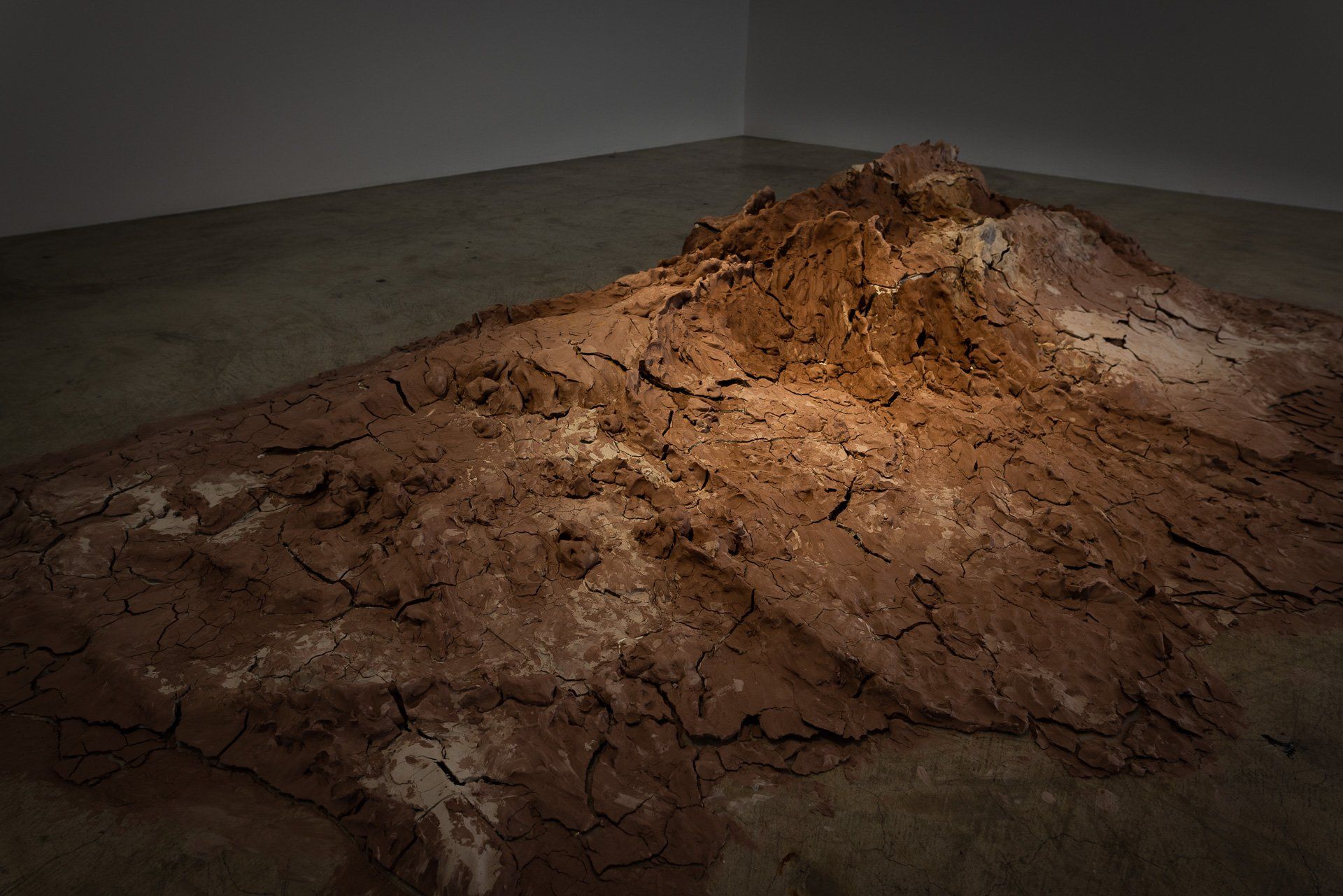 A large pile of dirt is sitting on the floor in a dark room.