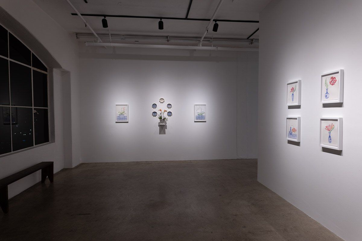 A large empty room with a bench and paintings on the wall.