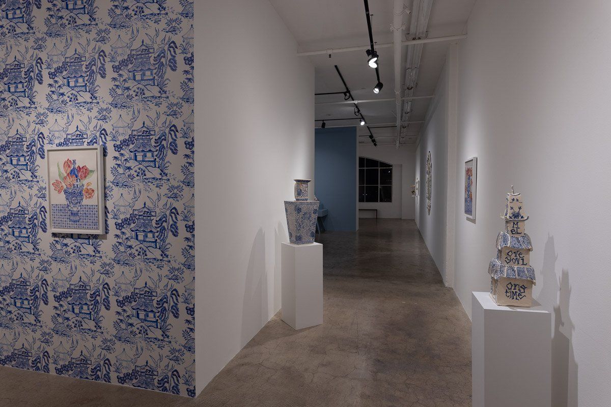 A hallway with a painting on the wall and vases on display.