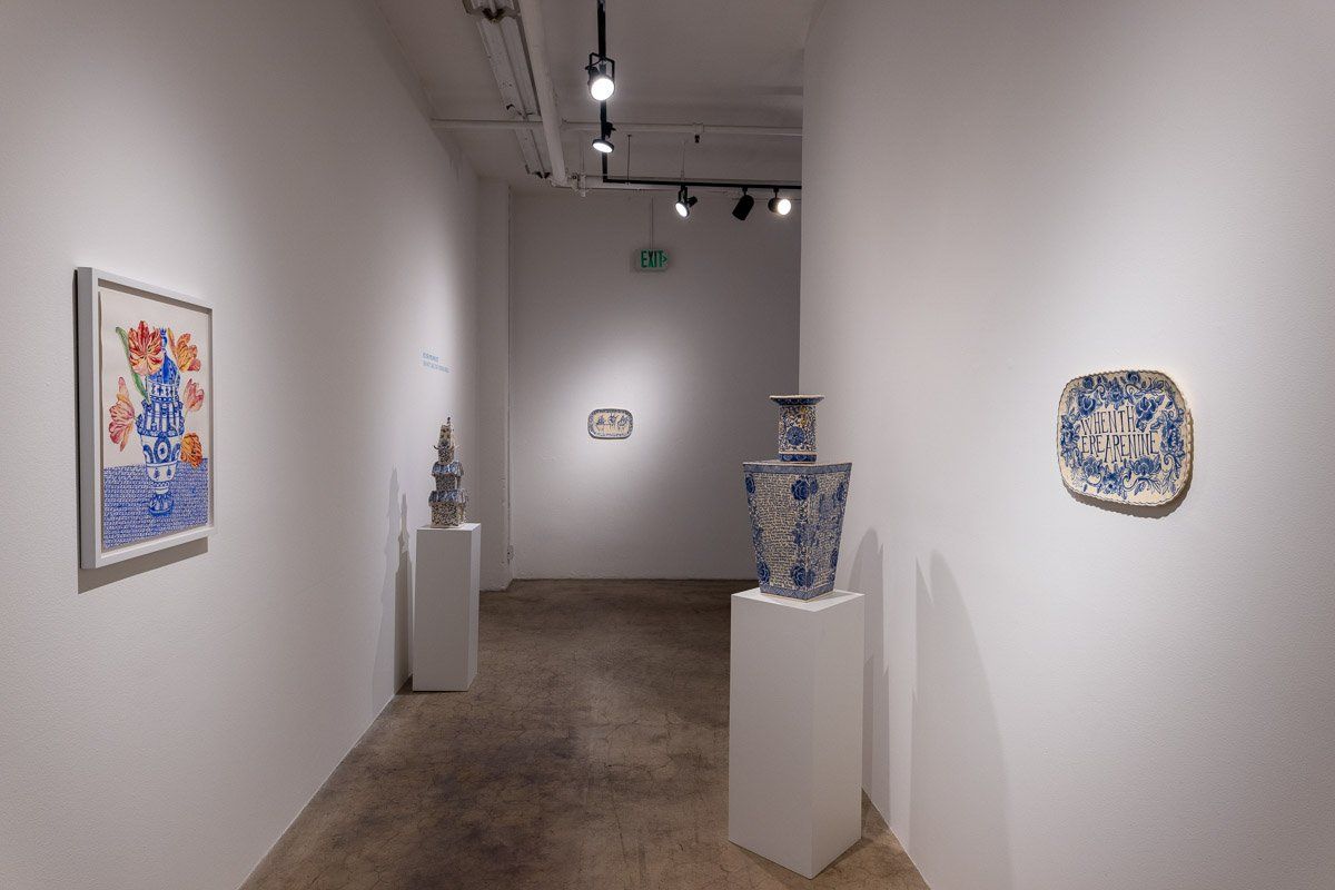 A hallway with a painting on the wall and a vase on a pedestal.