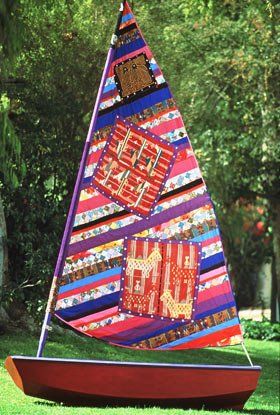 A colorful sailboat is sitting on the grass in a park