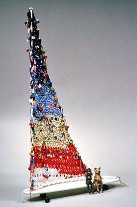A sculpture of a boat made of beads is sitting on a table.