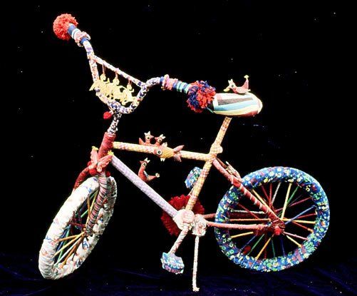 A colorful bicycle made out of yarn on a black background