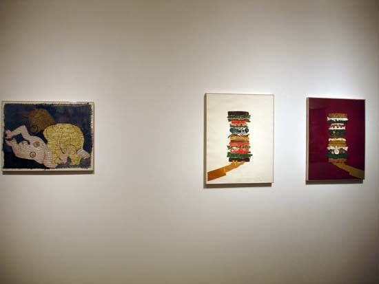 Three paintings are hanging on a wall in a museum