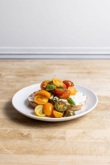 A plate of food with tomatoes and cheese on a wooden table.