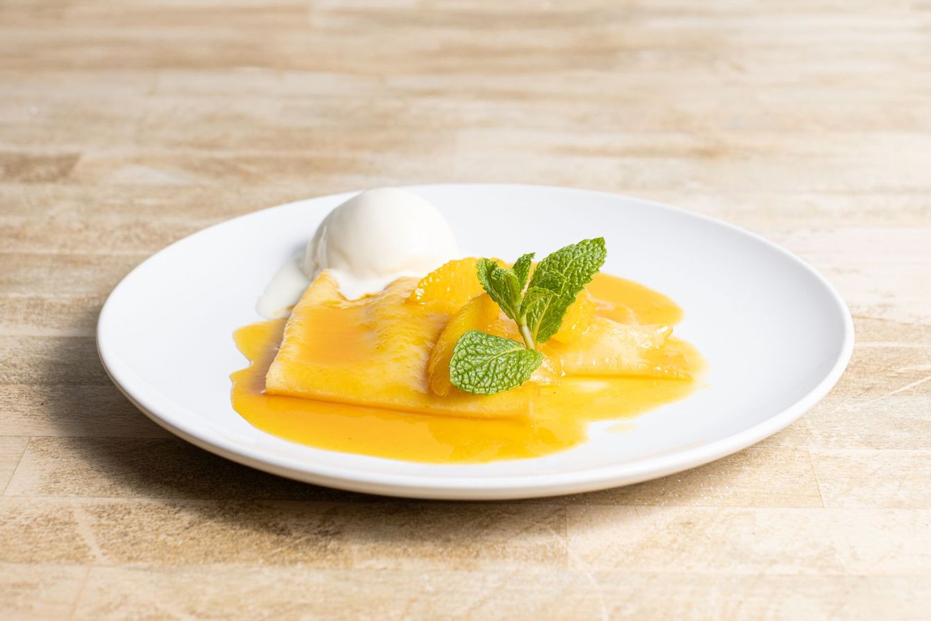 A white plate topped with a dessert and ice cream on a wooden table.