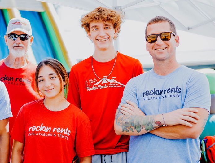 A group of people wearing rockin rents shirts are posing for a picture