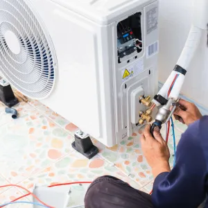 Happy Heating and Cooling LLC - A man is working on an air conditioner on the floor.