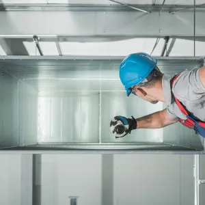 Happy Heating and Cooling LLC - A man wearing a hard hat and gloves is working on a ceiling.
