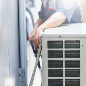 Happy Heating and Cooling LLC - A man is working on an air conditioner outside of a building.