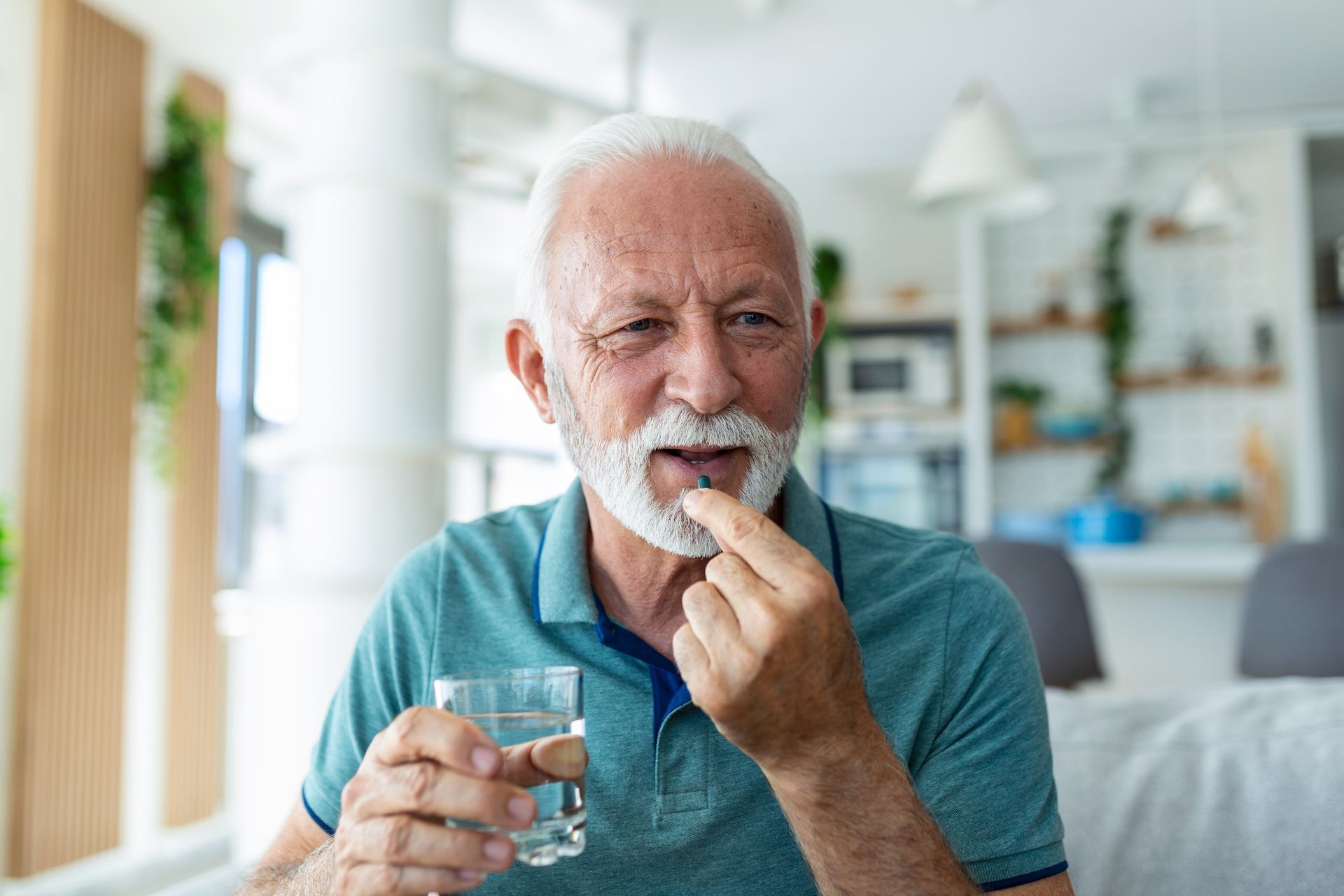Man holding a pill and a glass of water