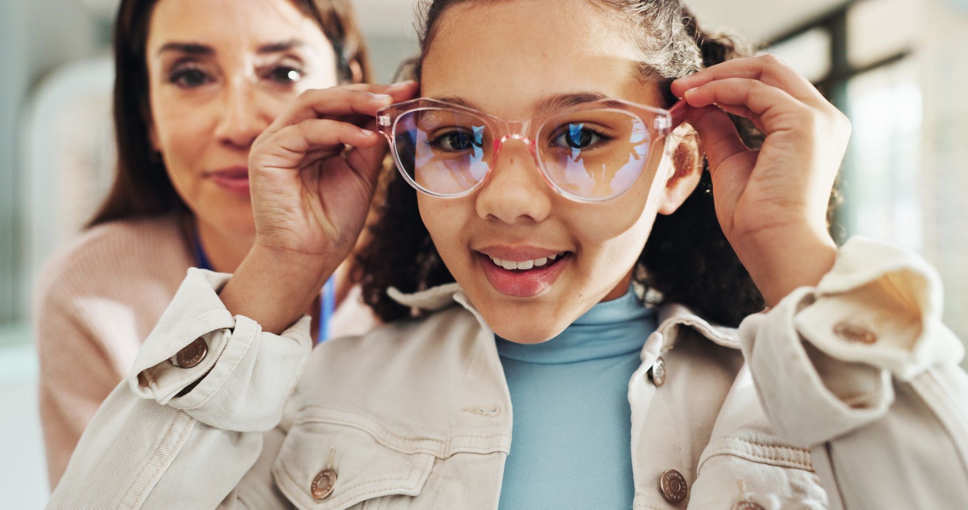 Woman adjusting eyeglasses on a child indoors