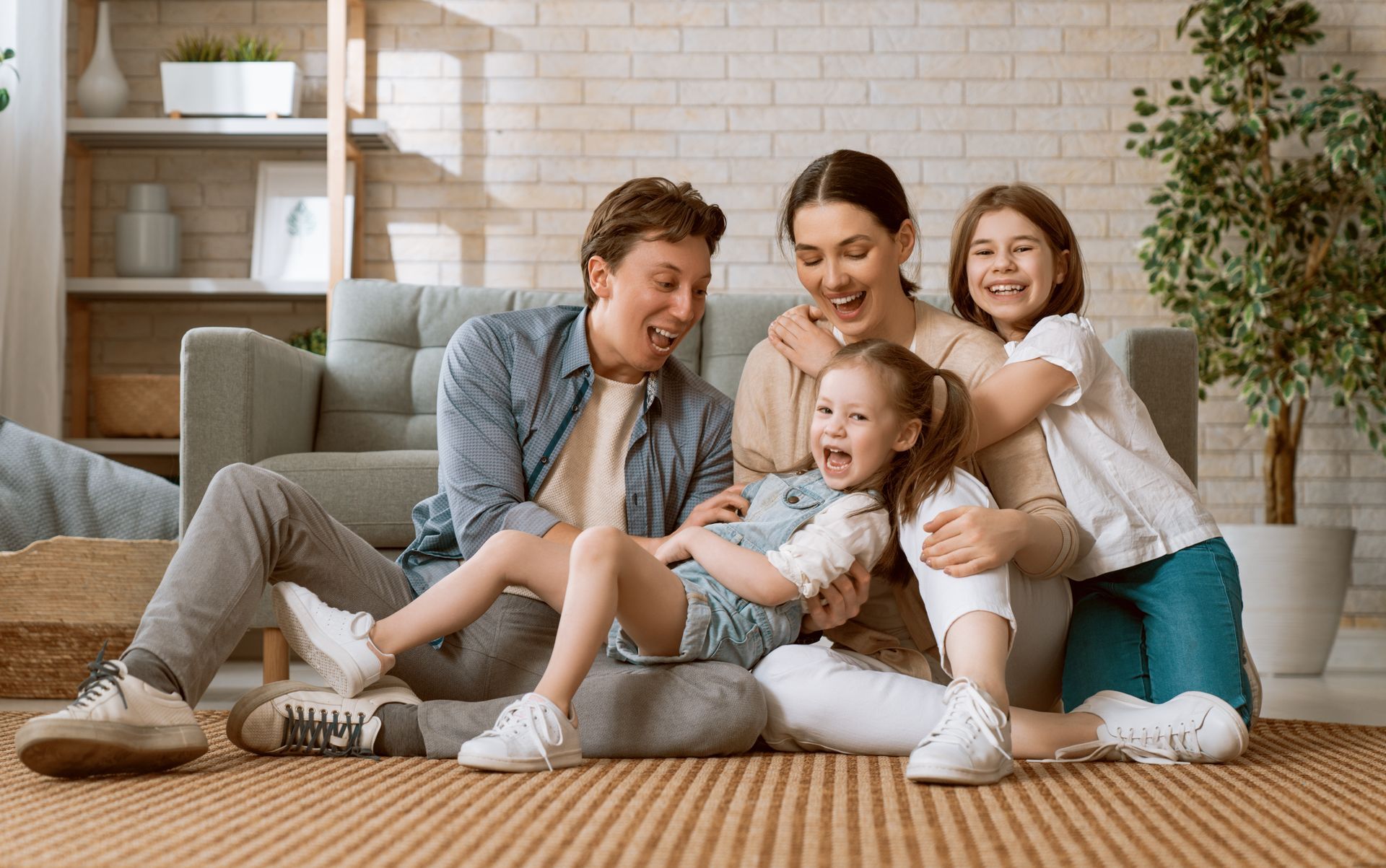 Family laughing together on the floor in front of a couch