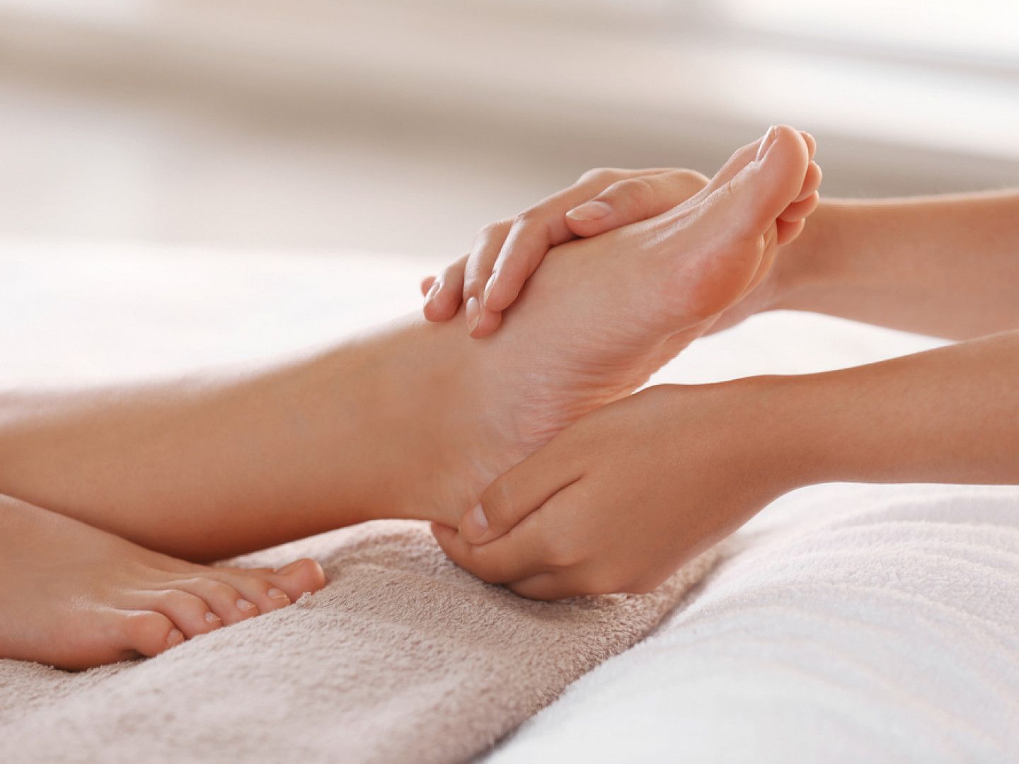 Hands giving a foot massage on a towel in a spa setting