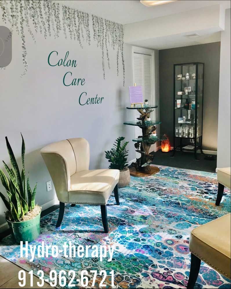 Cozy spa waiting room with cream chairs, colorful rug, plants, and “Color Care Center” wall sign