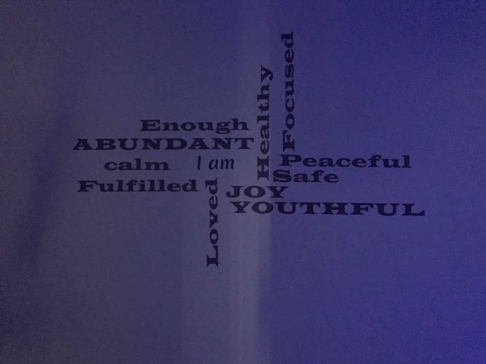Purple background with words “ABUNDANT,” “JOY,” “YOUTHFUL,” “peaceful,” and “calm” arranged in a cross shape