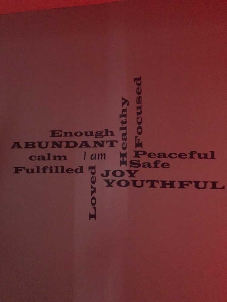 Pink wall with inspirational word art arranged in black text, including “Abundant,” “Peaceful,” and “Youthful.”