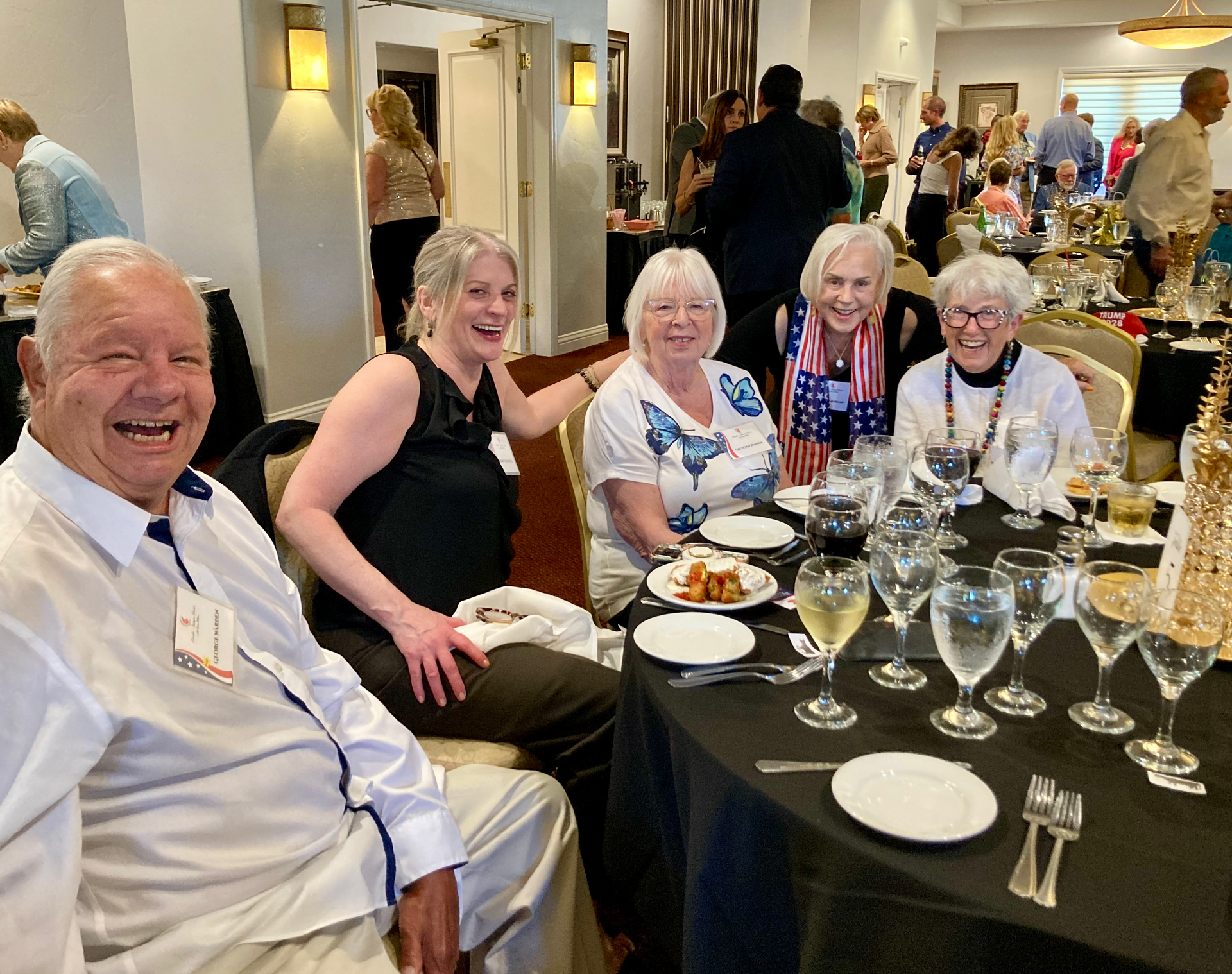 Five people seated at a banquet table, smiling at a formal indoor event