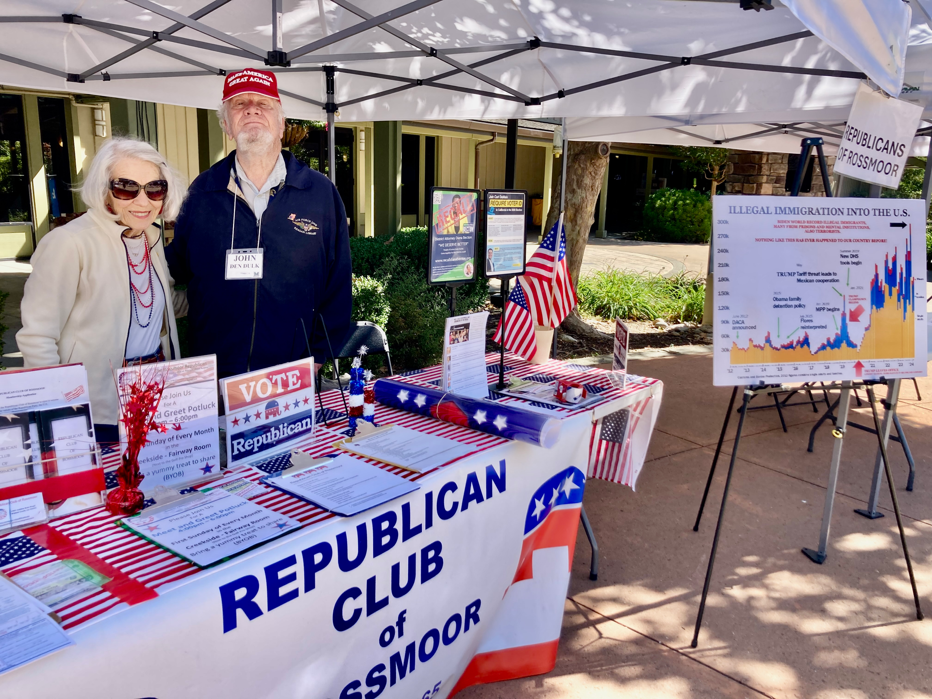 Republican Club booth with two volunteers, campaign signs, and an election poster under a canopy