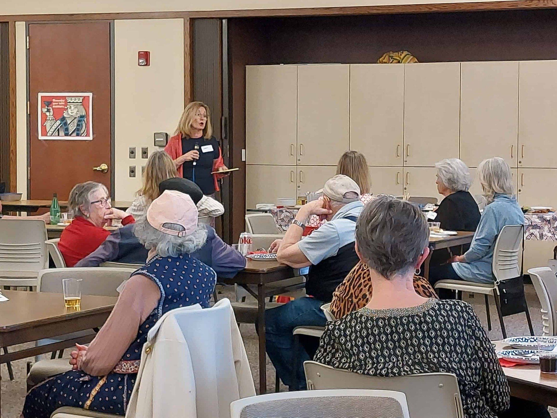 Woman speaking to a seated group in a community meeting room