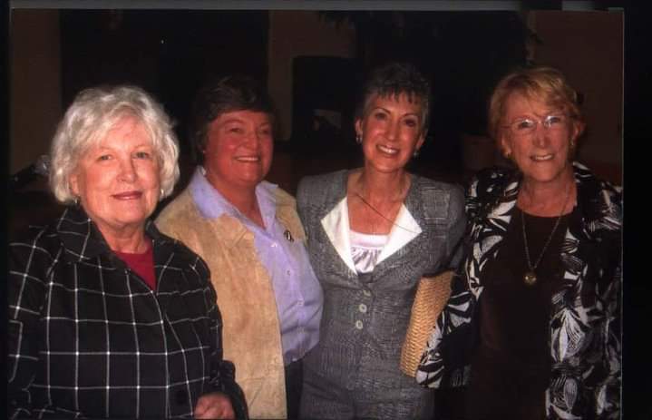 Four people posing indoors, smiling in semi-formal attire.
