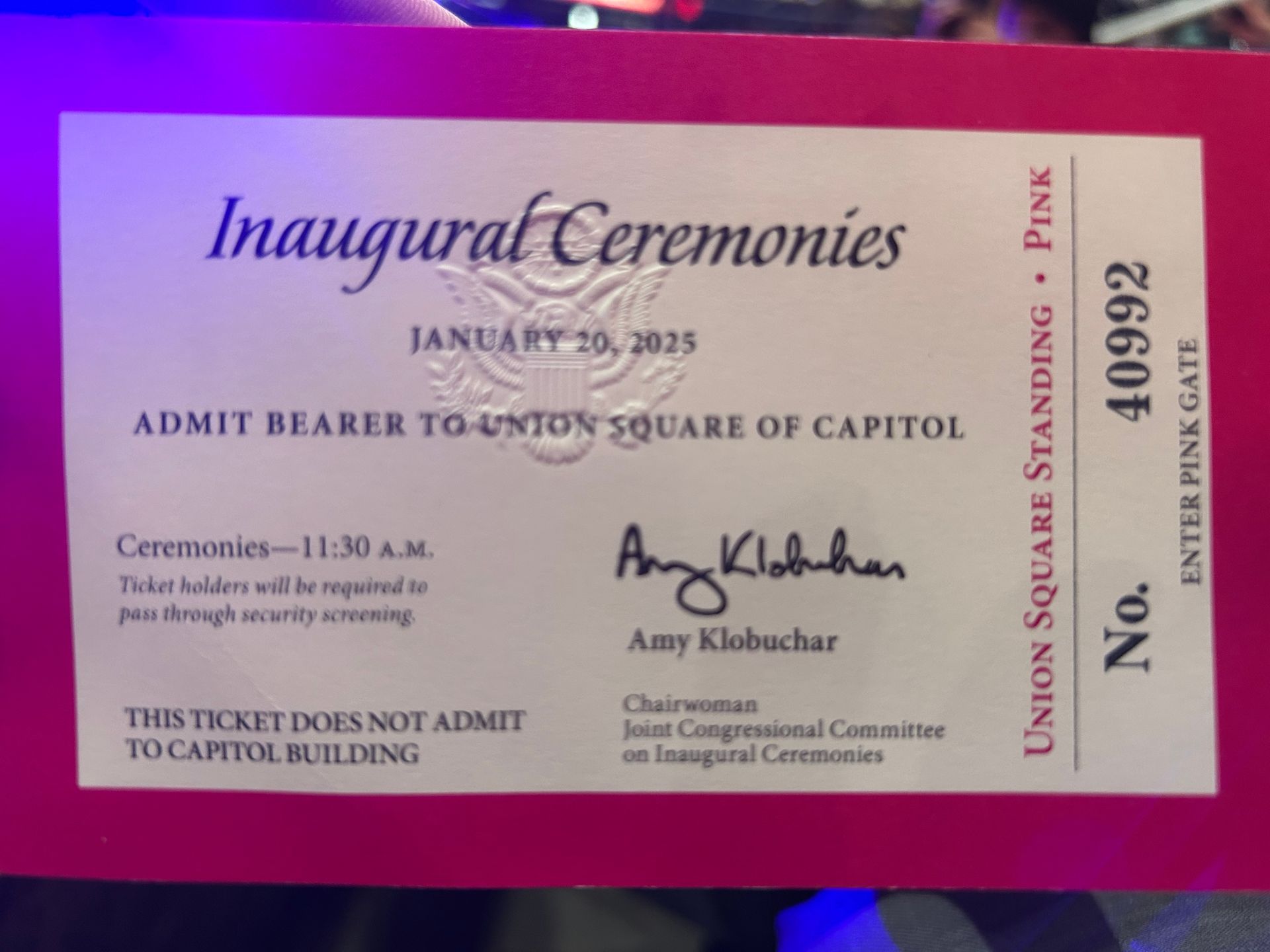 Pink and white inaugural ceremonies ticket for January 20, 2025, with printed admit-bearer text and signatures