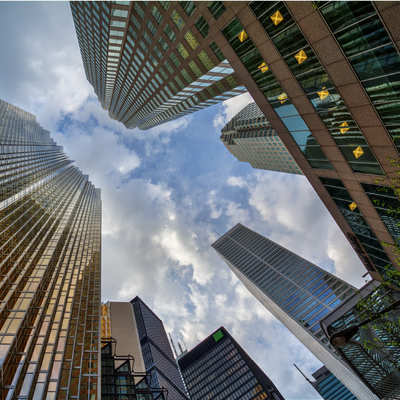 Skyscrapers towering inward against a cloudy sky in a city canyon view