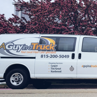 White A Guy in a Truck carpet cleaning van parked outdoors with logo and contact number on the side
